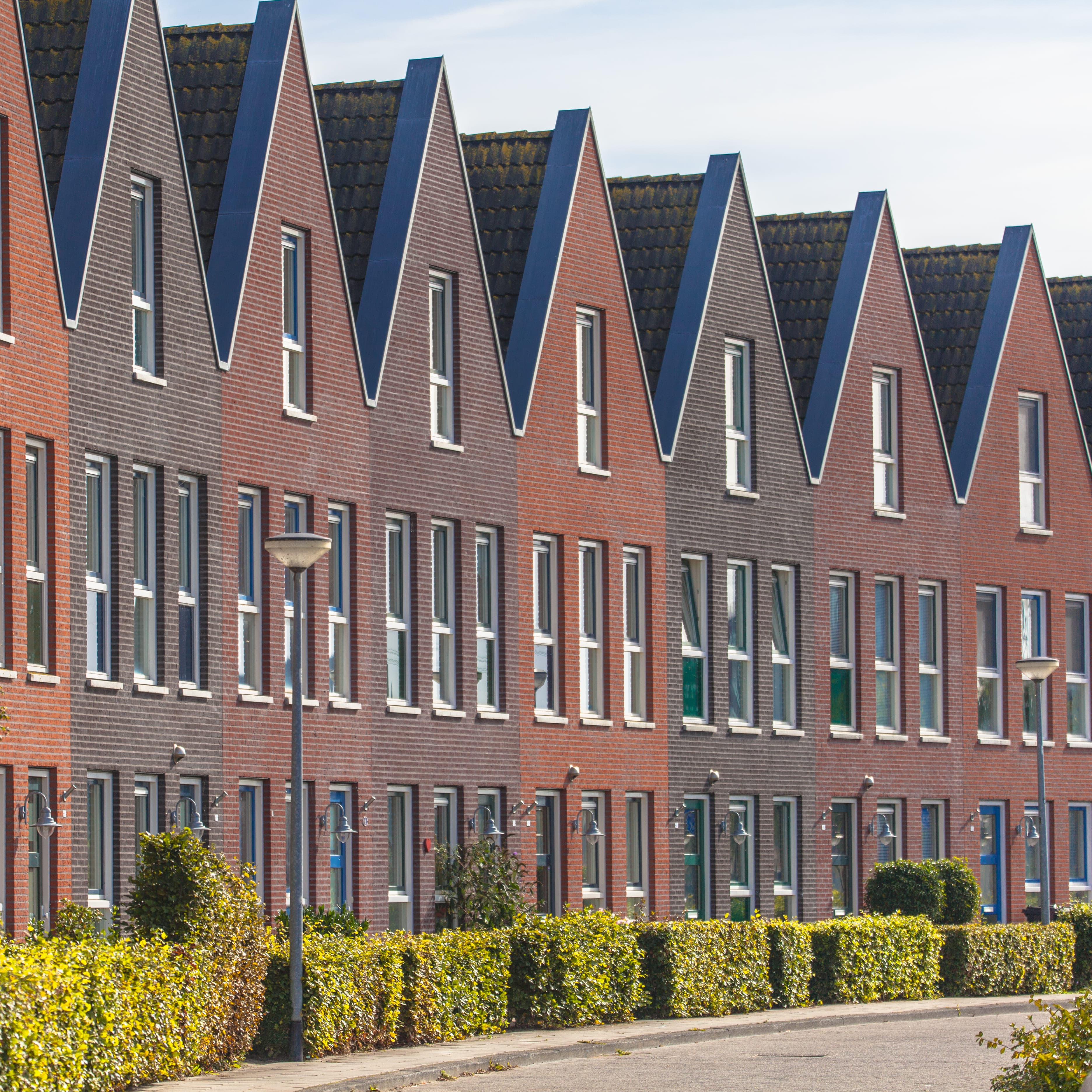 Row of townhomes on a residential street with hedgerows — real estate investment property