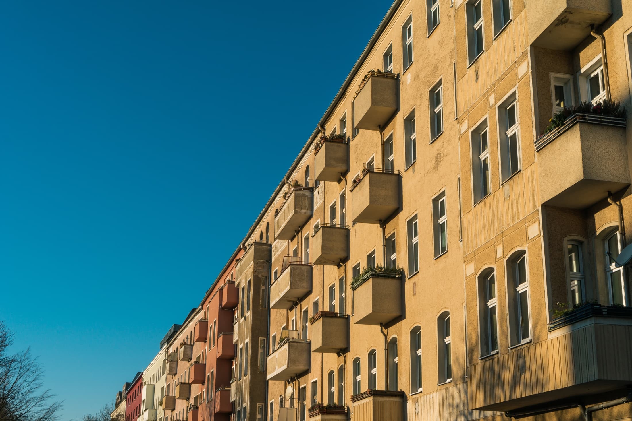 Exterior facade of a multi-story residential apartment building with balconies under a clear blue sky